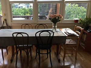 Photograph of a kitchen table with sunny windows behind it